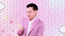 a man in a pink suit is dancing in front of a pink background with polka dots .