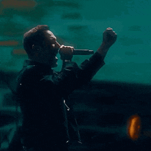 a man is singing into a microphone with his fist in the air