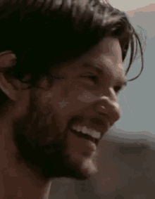a close up of a man 's face with a beard laughing .