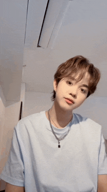 a young man wearing a necklace and a light blue shirt