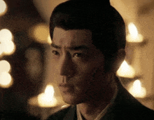 a close up of a man 's face in front of candles in a dark room .