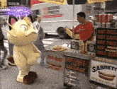a man in a red shirt stands behind a hot dog stand