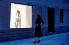 a woman is standing in front of a store window with a mannequin in it