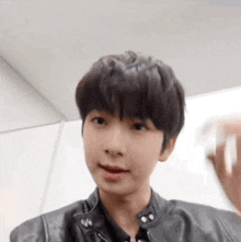 a young boy is wearing a black leather jacket and looking at the camera .