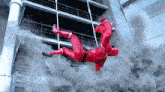 a man in a red suit is falling from a building .