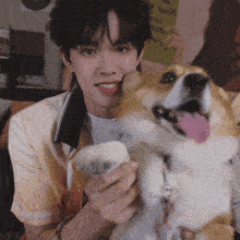 a young man is holding a dog with a pink tongue out