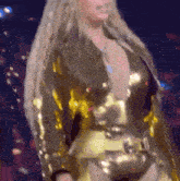 a woman with long blonde hair is wearing a very revealing gold outfit