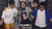 a group of people are standing around a man in a t-shirt that says damn you .