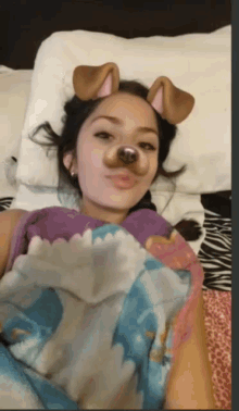 a woman wearing a dog face mask is laying in bed