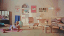a woman is doing exercises on a yoga mat in a living room with a sign that says strong women