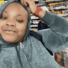 a woman wearing a hoodie and a red wristband is smiling in a store .