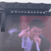 a man is holding a bottle of water in front of a microphone on a stage