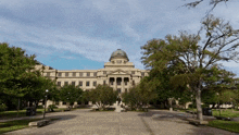 a large building with a dome on top is surrounded by trees and grass