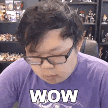 a man wearing glasses and a purple shirt with the word wow on it