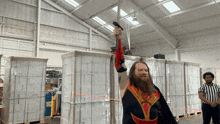 a man holding a sword in a warehouse with a referee standing nearby
