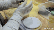 a person wearing white gloves is holding a piece of dough on a scale that says kg on it