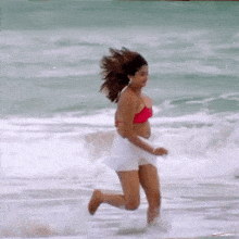 a woman in a bikini is running on the beach .