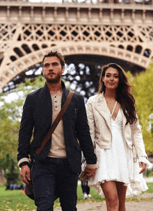 a man and a woman walking in front of the eiffel tower