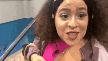 a woman with curly hair is wearing a pink shirt