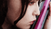 a close up of a woman 's face with a pink object in the foreground