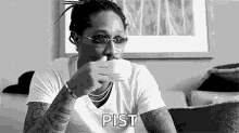 a man is drinking a cup of coffee while sitting on a couch .