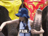 a woman in a blue hat is hugging an elephant with the words pain written on it