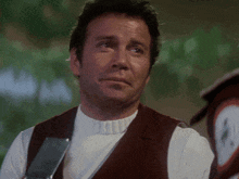 a man wearing a white shirt and a brown vest is looking down