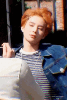 a man with red hair is wearing a striped shirt and a denim jacket ..