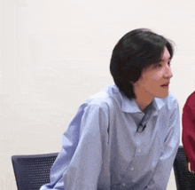 a man in a blue shirt is sitting in a chair with his back to the camera