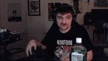 a man wearing headphones is sitting at a desk with a bottle of soda in front of him .