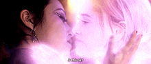two women are kissing each other in front of a purple background .