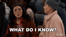 two women sitting in a crowd with the words what do i know written on the screen