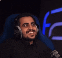 a man wearing headphones is sitting in front of a microphone .