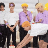 a group of young men are standing around a cake with candles