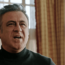 a man wearing a black turtleneck sweater is making a face