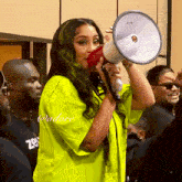 a woman in a neon yellow shirt is holding a megaphone in front of a group of people