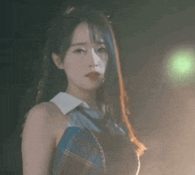 a woman in a plaid shirt and tie is standing in front of a green light .