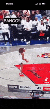 a woman is jumping in the air on a basketball court while a crowd watches .