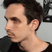 a close up of a man 's face with a black shirt on and a beard .
