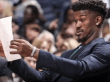 a man in a suit holds up a piece of paper