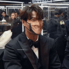 a man in a tuxedo is wearing a face mask that looks like a smiling face