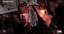 a man in a white robe is walking through a crowd of people in a wrestling ring .
