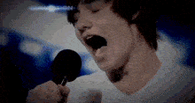 a man singing into a microphone with the word in motion in the corner