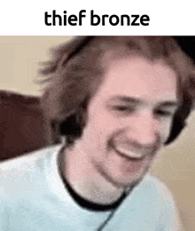 a man wearing headphones is smiling and looking at the camera with the words `` thief bronze '' above him .
