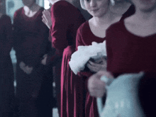 a woman in a red dress is holding a baby