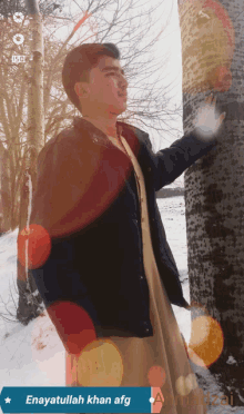 a man leaning against a tree in the snow with the words enayatullah khan afg written below him