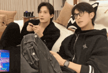 two men sitting on a couch playing a game