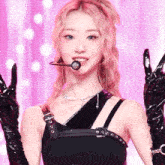 a woman wearing a black top and black gloves is giving the peace sign