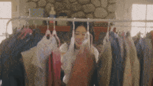 a woman is standing in front of a rack of clothing