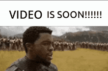a man is standing in a field with a crowd of people behind him and the words video is soon .